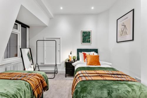 Lovely Penthouse in Worthing - Sleeps 6 في وورثينغ: غرفة نوم بسريرين وملاءات برتقالية وأخضر