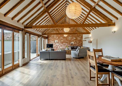 a living room with wooden ceilings and a brick wall at Barley Barn in Kimberley