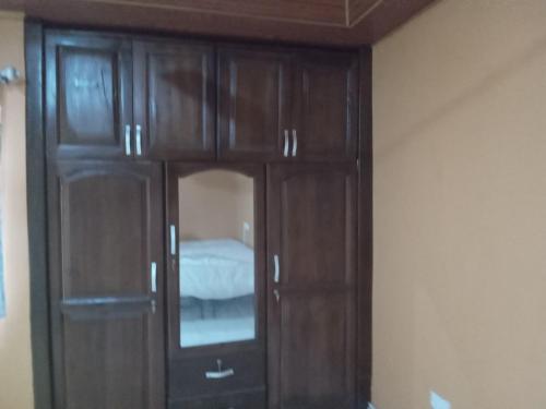 a wooden cabinet with a mirror in a room at Captivating 1-Bed Lodge in Accra in Accra