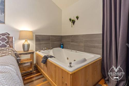 a bath tub in a bedroom next to a bed at Le1617 - Quai privé, Lac-Les chalets dans le nord in Sainte-Lucie-de-Doncaster