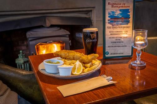 une table avec une assiette de nourriture et un verre de bière dans l'établissement Reddans of Bettystown Luxury Bed & Breakfast, Restaurant and Bar, à Bettystown