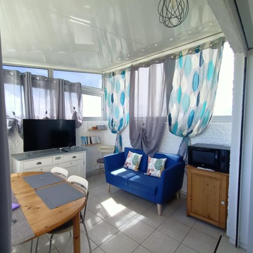 un salon avec un canapé bleu et une table dans l'établissement Studio les pieds dans l'eau App n°7, au Barcarès