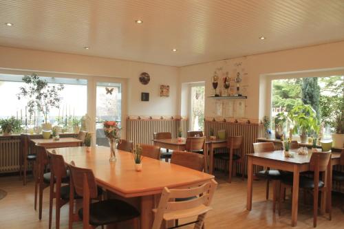 un restaurante con mesas y sillas de madera y ventanas en Pension Bartz, en Traben-Trarbach