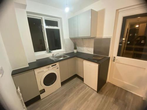 a kitchen with a sink and a washing machine at Stunning executive apartment. in London