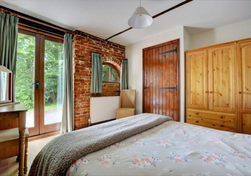 a bedroom with a bed and a brick wall at The Stables in Elsing