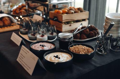 a table topped with bowls of desserts and pastries at OTTO Hotel & Sun in Pāvilosta