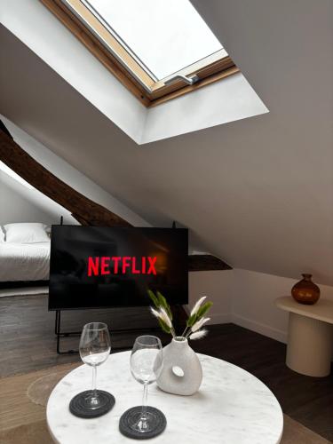 - un salon avec une télévision et 2 verres à vin dans l'établissement Ravissant studio parisien, à Paris