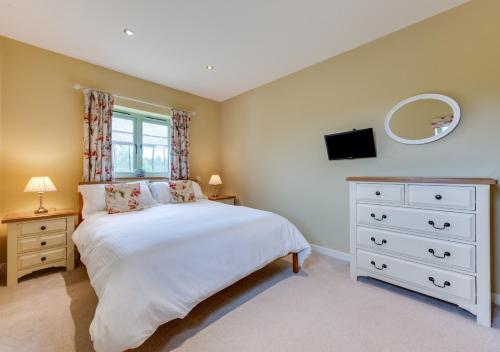 a bedroom with a bed and a dresser and a mirror at Partridge Lodge in Reepham