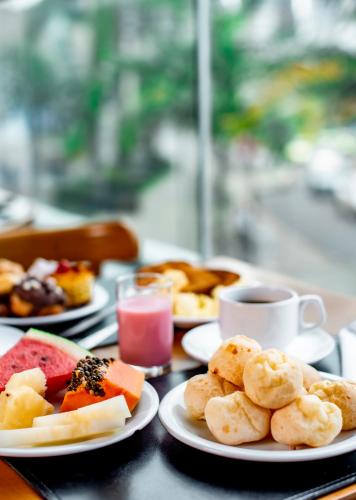 une table avec des assiettes de nourriture et une tasse de café dans l'établissement Trade Hotel, à Juiz de Fora