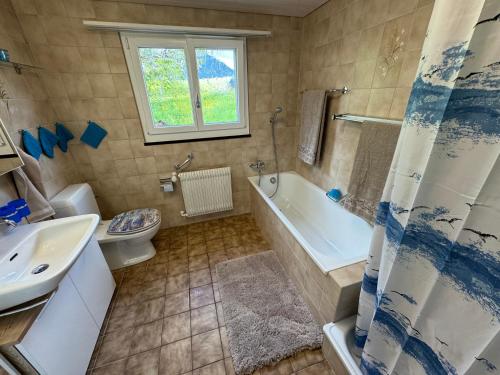ein Badezimmer mit einer Badewanne, einem WC und einem Waschbecken in der Unterkunft See und Berge Family in Faulensee