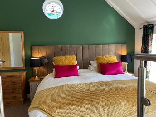 um quarto com uma cama grande e almofadas cor-de-rosa em Willow Mews em Swansea