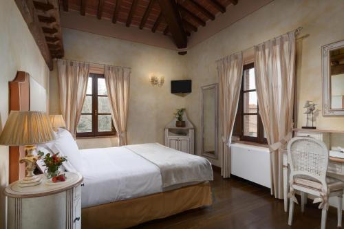 a bedroom with a bed and a desk and two windows at Relais la Leopoldina in Bettolle