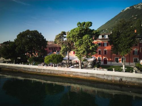 a river in front of a building next to a building at Hotel Bogliaco in Gargnano