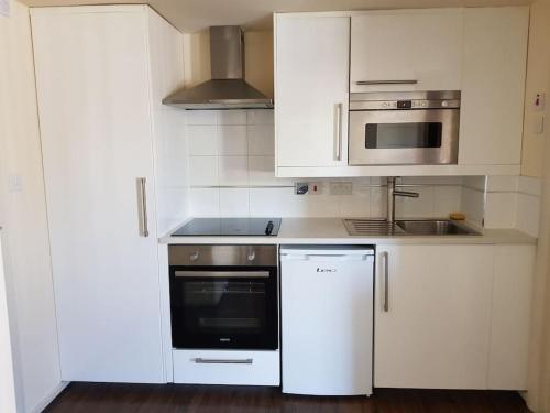 a white kitchen with a stove and a microwave at Studio flat London in London