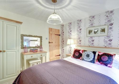 1 dormitorio con 1 cama con almohadas rosas y moradas en The Cottage en Scole