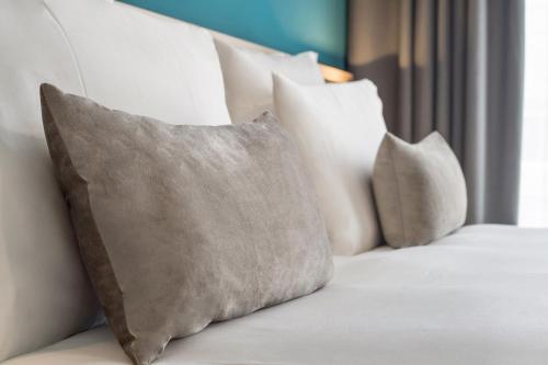 a white couch with four pillows on it at Appart'City Collection Genève Aéroport - Vernier in Geneva