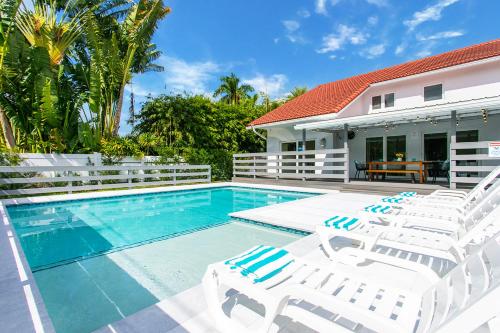 ein Swimmingpool mit weißen Stühlen und einem Haus in der Unterkunft Luxury Villa 5BR and 3BR in Hollywood Lakes near Beach in Hollywood