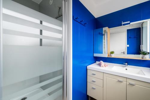 y baño con paredes azules, lavabo y ducha. en RDC FACE A LA MER, en Dunkerque