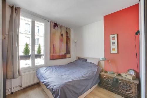une chambre avec un lit et une fenêtre dans l'établissement SUPERBE DUPLEX avec JARDIN PARTAGE à PARIS MENILMONTANT, à Paris