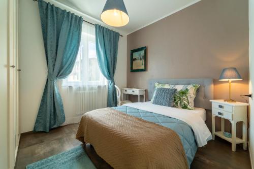 um quarto com uma cama com cortinas azuis e uma janela em Ka' Doro with Lake View em Nesso