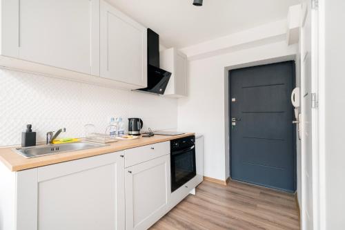 uma cozinha com armários brancos e uma porta azul em Nawrot Cosy Studio em Łódź