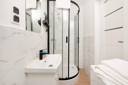 biała łazienka z prysznicem i umywalką w obiekcie Nawrot Cosy Studio w Łodzi