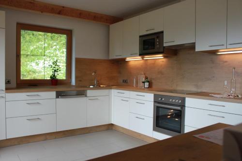 uma cozinha com armários brancos e uma janela em Ferienhaus Innerzarge em Tux