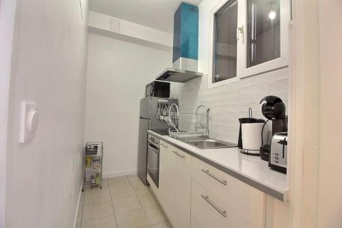 une cuisine blanche avec un évier et une cuisinière dans l'établissement Le Cocon De Pleyel, à Saint-Denis