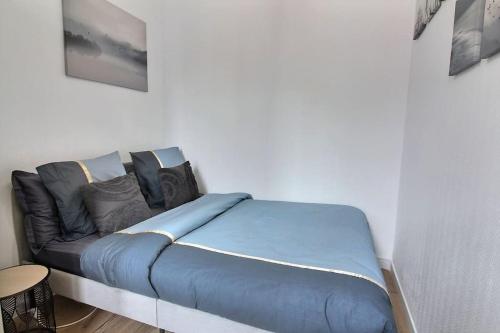 - un lit dans une chambre avec un canapé bleu dans l'établissement Le Cocon De Pleyel, à Saint-Denis