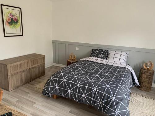 une chambre avec un lit avec une couette noire et blanche dans l'établissement La maison du lavoir, à Fain-lès-Montbard
