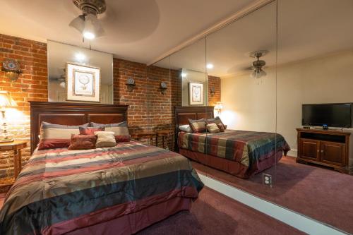 1 dormitorio con cama, espejo y TV en Quarter House Suites en Nueva Orleans