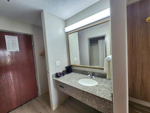 a bathroom with a sink and a mirror at Days Inn by Wyndham Lafayette Scott in Lafayette