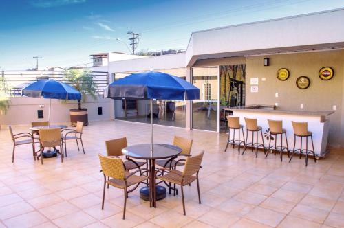 a patio with tables and chairs with blue umbrellas at Garden Hotel in Ribeirão Preto