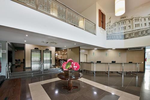 a lobby with a waiting room with pink flowers on a table at Garden Hotel in Ribeirão Preto