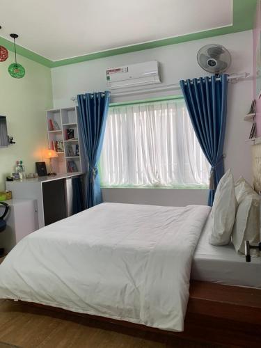 a bedroom with a large bed with blue curtains at Mio Hotel in Hải Dương