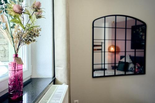 a vase with flowers on a table next to a mirror at LIVING Apartments / FeWo Neuwied in Neuwied