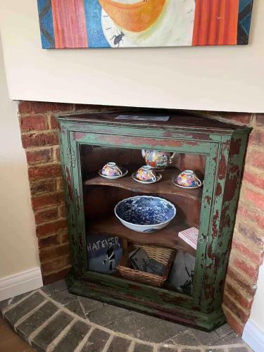 a fireplace with a shelf with dishes in it at 3-bed cottage in Sway, New Forest (5 min walk from Sway Train Station) in Sway