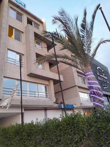 um edifício com uma palmeira em frente em Coast Hotel em El Alamein