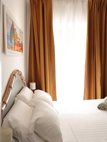a bedroom with a bed with white pillows and a window at Hotel Terme Oriente - Beach & SPA in Ischia