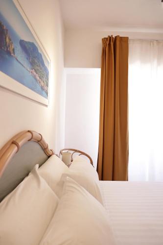 a bedroom with a bed with white sheets and a window at Hotel Terme Oriente - Beach & SPA in Ischia