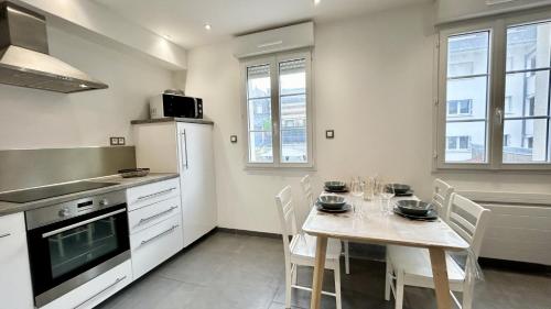 Il comprend une cuisine équipée d'une table avec des chaises et d'un réfrigérateur blanc. dans l'établissement Les bateaux, duplex 4 personnes proche plage, au Crotoy