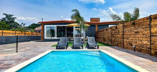 a swimming pool with two chairs and a house at Villas turísticas del noroeste in Villanueva de Arosa