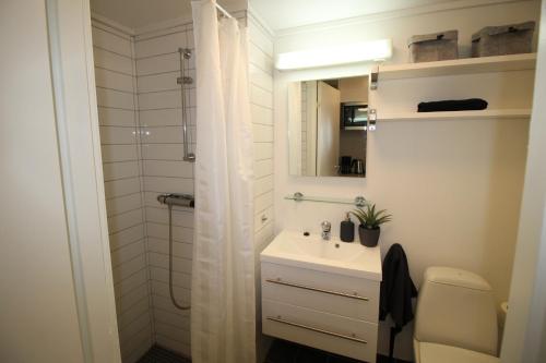 ein weißes Bad mit einem Waschbecken und einer Dusche in der Unterkunft Kongensgate Apartments in Kristiansand