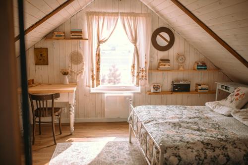1 dormitorio con cama, escritorio y ventana en Siedlisko Niezapominajka - domek z basenem i balią, 