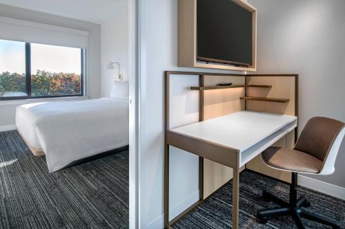 a hotel room with a bed and a desk and a tv at TownePlace Suites By Marriott Wrentham Plainville in Wrentham