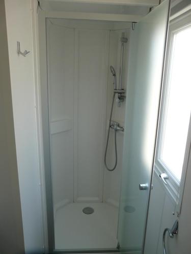 y baño blanco con ducha y ventana. en Mobil-Home pour 6 personnes (3 chambres), en Narbona