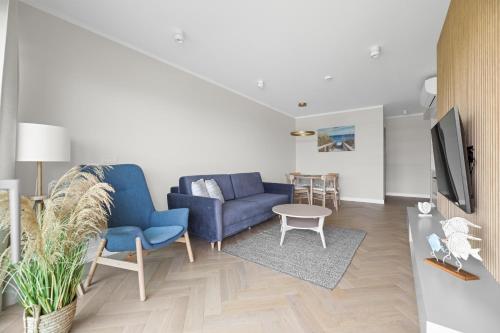 a living room with a blue couch and a tv at Solaris Darłówko Premium Emilia Strupiechowska in Darłowo