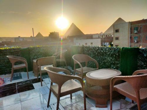 un grupo de sillas y mesas en un balcón con pirámides en Migo Pyramids View, en El Cairo