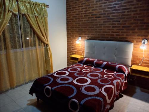 1 dormitorio con 1 cama con 2 lámparas y pared de ladrillo en 4 Estaciones en Pergamino