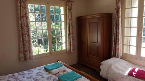 a bedroom with a bed and two windows at Le Chalet du Moulin Blanc in Bergerac